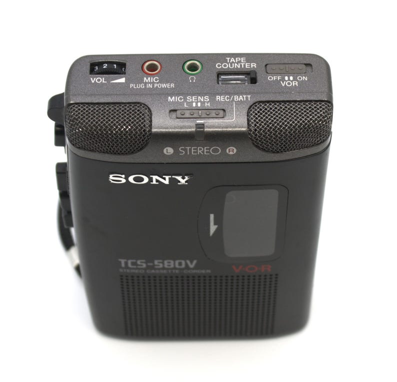 May include: A black Sony TCS-580V stereo cassette recorder with a built-in microphone and speaker grilles. The device has a tape counter, volume control, and various input/output jacks. The model name and brand are visible on the front.