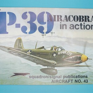 May include: A vintage book cover featuring a green and yellow P-39 Airacobra fighter plane in flight. The cover is titled "P-39 Airacobra in action" and includes the text "squadron/signal publications AIRCRAFT NO. 43".