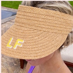 May include: A woven straw visor with a wide brim. The visor has the yellow letters "LF" embroidered on the front. The image also shows a second visor with the text "Your monogram here!"