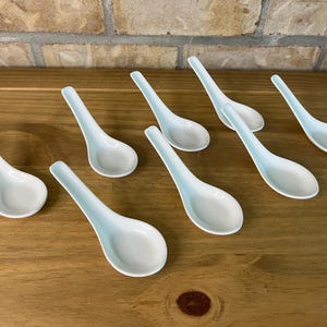 Peut inclure: Un ensemble de sept cuillères à soupe en céramique blanche avec une finition lisse et brillante. Chaque cuillère présente un bol profond et arrondi ainsi qu'un long manche incurvé, conçu pour servir ou manger des plats à base de bouillon.