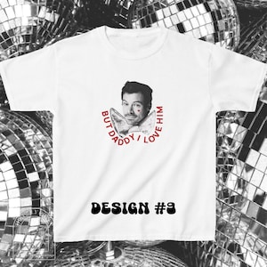 Puede incluir: Una camiseta blanca de manga corta con un retrato en blanco y negro de un hombre con un peque&ntilde;o coraz&oacute;n rojo en la mejilla. Debajo del retrato hay una pajarita y el texto rojo BUT DADDY I LOVE HIM. DESIGN #9 est&aacute; impreso debajo.