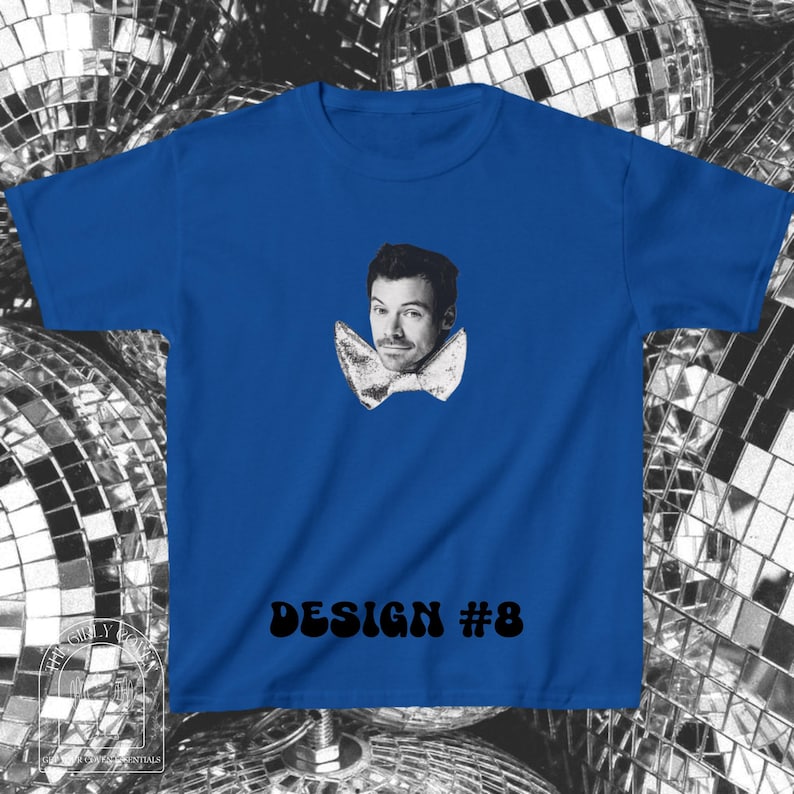 Puede incluir: Una camiseta de manga corta color azul real con un retrato fotogr&aacute;fico en blanco y negro de un hombre que lleva una pajarita grande y texturizada. El texto "DESIGN #8" est&aacute; impreso en letras negras negritas en la parte inferior.