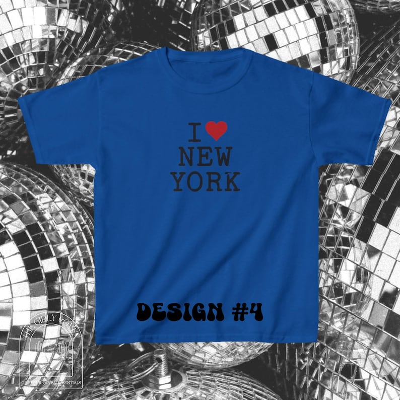 Puede incluir: Una camiseta de manga corta color azul real con el texto en negro I NEW YORK, donde un coraz&oacute;n rojo sustituye a la palabra LOVE. En la parte inferior de la camiseta aparece el texto en negro DESIGN #4 con una fuente retro, negrita y redondeada.