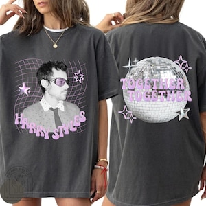Puede incluir: Una camiseta gris carbón con un gráfico de Harry Styles usando gafas de sol moradas en el frente, con el texto "Harry Styles" en rosa. La parte posterior muestra un gráfico de una bola de discoteca con el texto "TOGETHER TOGETHER" en rosa.