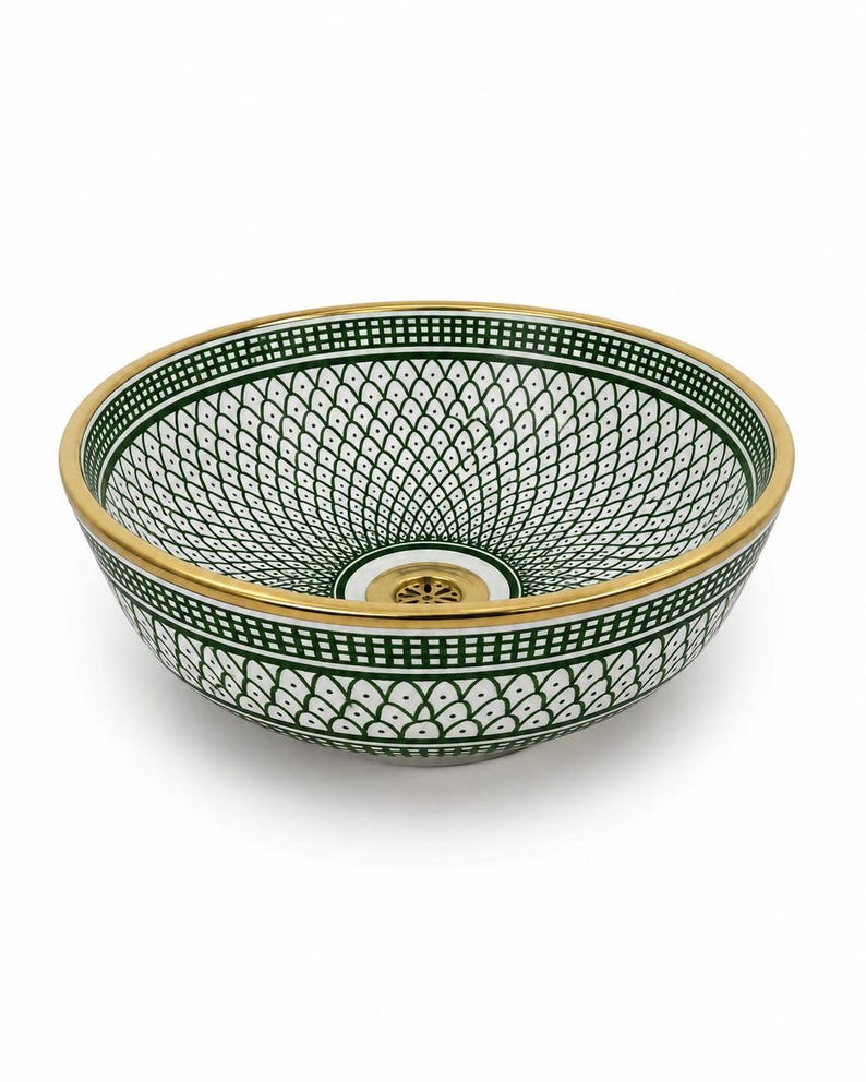 May include: A decorative ceramic sink basin with a white and green geometric pattern. The rim and drain are gold-colored. The sink has a round shape and is designed for bathroom use.