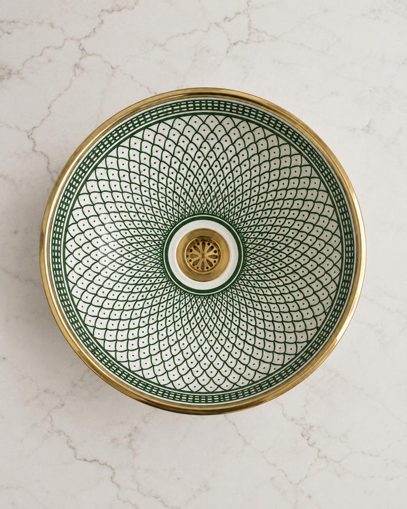 May include: A decorative sink basin with a gold rim and a white and green patterned interior. The basin features a central drain with a gold finish. The intricate design is a repeating pattern of green diamonds and dots.