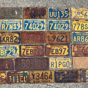 May include: A collection of 20 vintage Pennsylvania license plates, mostly yellow with blue lettering, with some rust and wear. The plates are arranged in rows and columns, and some of the plates have the year and state printed on them.