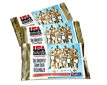 May include: Three sealed packs of SkyBox International USA Basketball trading cards. Each pack features a photo of the 1992 "Dream Team" with the text "The Greatest Team Ever Assembled".