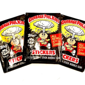 May include: Three packs of Garbage Pail Kids stickers. Each pack features a cartoon character with a bomb exploding above their head. The text on the packs reads "Garbage Pail Kids", "Topps", "25¢ Cheap", "All New! 5th Series", and "Stickers".