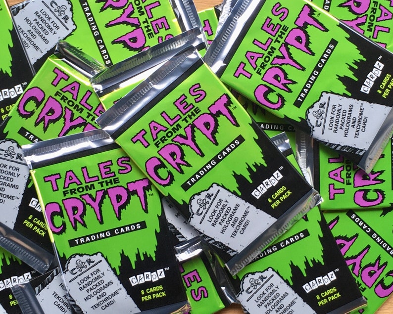 Puede incluir: Una pila de paquetes de cartas coleccionables sellados con el tema Tales from the Crypt. Los paquetes son verdes con texto negro y rosa. Cada paquete contiene 8 cartas e incluye hologramas y cartas tekchrome empaquetados aleatoriamente.