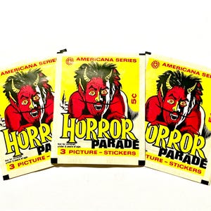 May include: Three vintage "Horror Parade" sticker packs. Each pack features a red devil illustration on a yellow background, with the text "Horror Parade" and "3 Picture-Stickers". The packs are from the "Americana Series".