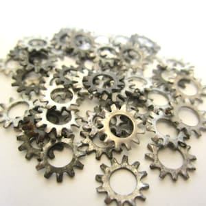 May include: A close-up of a pile of silver metal star-shaped washers. The washers are arranged in a random pattern and are all the same size.