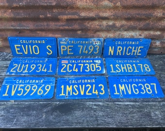 May include: Nine vintage California license plates with blue backgrounds and yellow lettering. The plates feature various license plate numbers and the words "California" and "NOV", "MAR", and "CA 31".