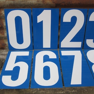 May include: Ten blue and white numbered signs with white numbers on a blue background. The numbers are 0 through 9.