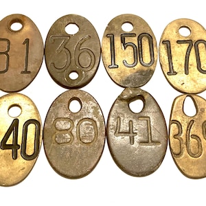 May include: Eight brass oval-shaped tags with holes and numbers 81, 36, 150, 170, 140, 80, 41, and 369.