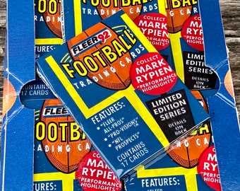 May include: A box of Fleer '92 Football Trading Cards, featuring a football graphic. The box is blue, yellow, and orange, with text that reads "Limited Edition Series" and "Collect Mark Rypien Performance Highlights". Contains 17 cards.