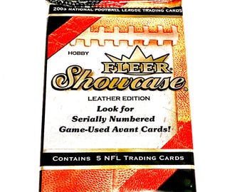 May include: A pack of 2003 Fleer Showcase Leather Edition NFL trading cards. The pack is red and black with a white football graphic and the text "Look for Serially Numbered Game-Used Avant Cards!"