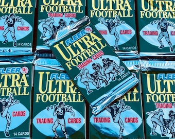 May include: A close-up of multiple sealed packs of 1991 Fleer Ultra Football trading cards. Each pack features a green background with a silver foil design and the text "Fleer 91 Ultra Football Trading Cards".