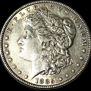 May include: A silver coin with a detailed profile of a woman, the word "LIBERTY" and the date "1885". The coin's edge features a series of stars. The words "E PLURIBUS UNUM" and "UNITED STATES OF AMERICA" are also visible.