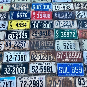 May include: A collection of vintage license plates from Iowa, featuring a variety of colors, numbers, and lettering. The plates are arranged in rows and columns, and some of them have faded or chipped paint. The plates are all from the state of Iowa, and they date back to the 1930s and 1940s.