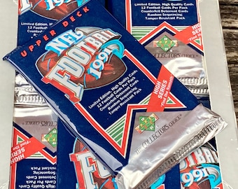 May include: A close-up of a sealed pack of 1991 NFL Upper Deck Football trading cards. The pack is blue and red with a silver foil wrapper. The text on the pack reads "Limited Edition. High Quality Cards. 12 Football Cards Per Pack. Counterfeit-Deterrent Cards. Random Sequencing. Tamper-Resistant Pack."