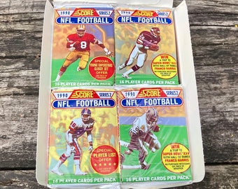 May include: Four unopened packs of 1990 Score Series 2 NFL Football trading cards. Each pack features a different football player on the front. The packs are white with red, blue, and yellow accents. The text on the packs reads "1990 Score Series 2 NFL Football" and "16 Player Cards Per Pack".