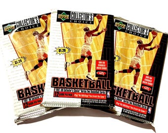May include: Three Upper Deck Collector's Choice basketball card packs. Each pack features a basketball player in action. The packs have the text "BASKETBALL" and "12 CARDS PER PACK". The price tag on two of the packs reads "$1.29".