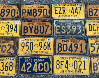 May include: A collection of vintage Pennsylvania license plates, featuring yellow and blue backgrounds with black lettering. The plates display various numbers and the Keystone State emblem, showcasing a weathered, aged appearance.