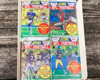May include: Four packs of 1990 Score Series 1 NFL Football trading cards. Each pack features a different football player on the front. The packs are all sealed and have a blue and yellow color scheme.