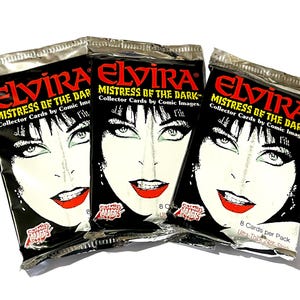 Puede incluir: Tres paquetes sellados de cartas coleccionables "Elvira, Mistress of the Dark". Cada paquete presenta un fondo negro con la cara de Elvira en blanco y l&aacute;piz labial rojo. Los paquetes est&aacute;n etiquetados como "Collector Cards by Comic Images".