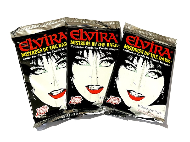 Puede incluir: Tres paquetes sellados de cartas coleccionables "Elvira, Mistress of the Dark". Cada paquete presenta un fondo negro con la cara de Elvira en blanco y l&aacute;piz labial rojo. Los paquetes est&aacute;n etiquetados como "Collector Cards by Comic Images".
