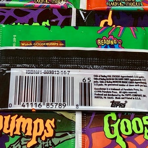 K&ouml;nnte beinhalten: Ein schwarzes und gr&uuml;nes Goosebumps Sammelkarten-Paket mit einem Barcode und dem Text "ISBN#1-883313-14-7" und "Watch GOOSEBUMPS on". Die R&uuml;ckseite des Pakets enth&auml;lt eine Liste der Wahrscheinlichkeiten, verschiedene Arten von Karten zu finden, darunter Folienaufkleber, im Dunkeln leuchtende Karten und Monster-Magiekarten.