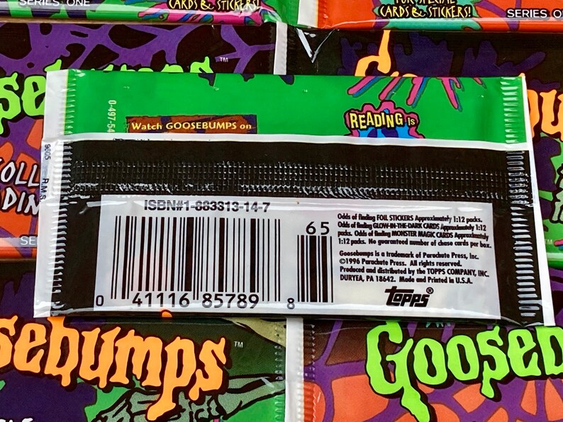 K&ouml;nnte beinhalten: Ein schwarzes und gr&uuml;nes Goosebumps Sammelkarten-Paket mit einem Barcode und dem Text "ISBN#1-883313-14-7" und "Watch GOOSEBUMPS on". Die R&uuml;ckseite des Pakets enth&auml;lt eine Liste der Wahrscheinlichkeiten, verschiedene Arten von Karten zu finden, darunter Folienaufkleber, im Dunkeln leuchtende Karten und Monster-Magiekarten.