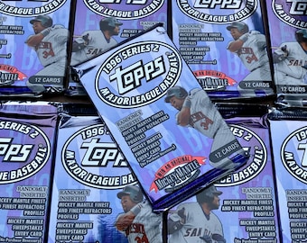 May include: A close-up of multiple sealed packs of 1996 Topps Series 2 Major League Baseball trading cards. The packs feature a purple and white design with a randomly inserted Mickey Mantle card.