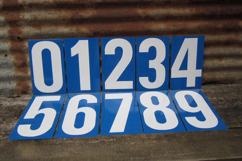 May include: Nine blue and white metal number plaques, each with a white number on a blue background. The numbers are 0 through 9.