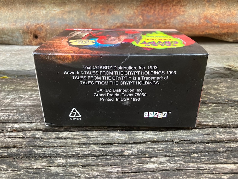 Puede incluir: Una caja negra con texto blanco que dice "Text &copy;CARDZ Distribution, Inc. 1993 Artwork &copy;TALES FROM THE CRYPT HOLDINGS 1993 TALES FROM THE CRYPT&trade; is a Trademark of TALES FROM THE CRYPT HOLDINGS. CARDZ Distribution, Inc. Grand Prairie, Texas 75050 Printed In USA 1993 OTHER CARDZ&trade;".