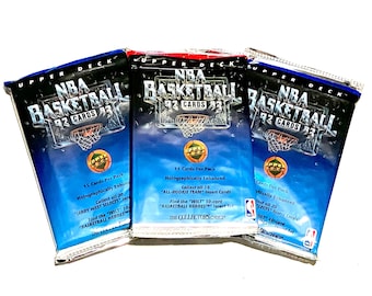Può includere: Tre pacchetti sigillati di carte da collezione di basket NBA Upper Deck del 1992. Ogni pacchetto presenta uno sfondo blu, rosso o nero con una palla da basket e il testo "NBA Basketball 92 Cards 93".