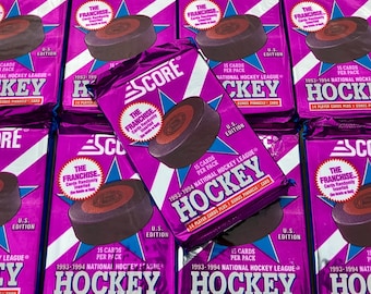 May include: A stack of unopened packs of 1993-1994 Score Hockey trading cards. The packs are purple and feature a hockey puck with a star and the text "The Franchise" and "Score".