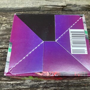 Puede incluir: Una caja de color morado, negro y verde con un c&oacute;digo de barras y el n&uacute;mero "46134 81546 1" impreso en el lateral.