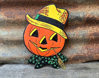 May include: Vintage Halloween decoration of a pumpkin with a straw hat and a green and black bow tie. The pumpkin has a friendly face with a yellow smile and black eyes.