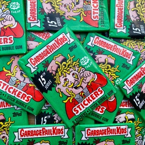 May include: A pile of green and white Garbage Pail Kids trading cards with a cartoon character on each card. The cards are from the 15th series and feature the text "Garbage Pail Kids" and "Stickers".