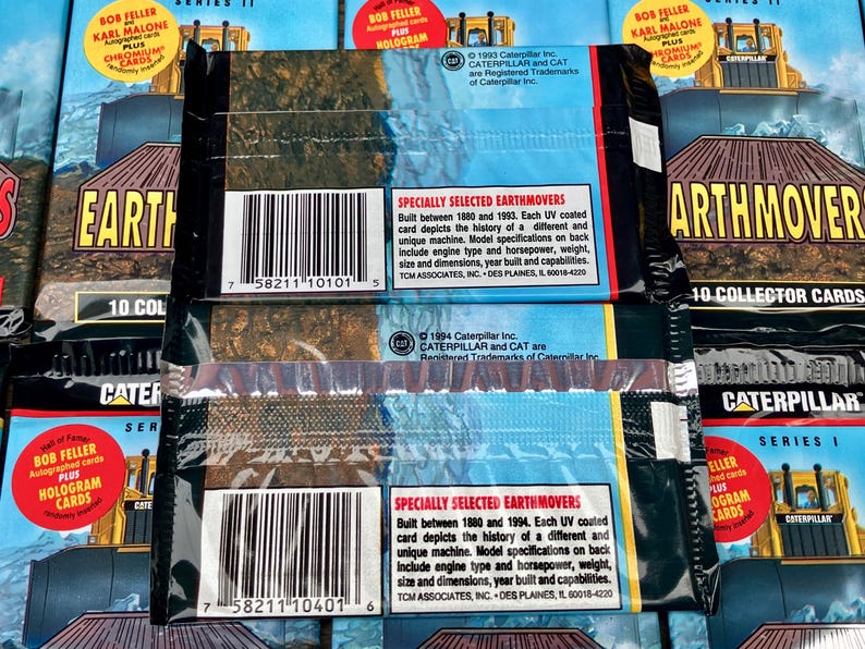 May include: Two unopened packs of Caterpillar Earthmover trading cards. Each pack features a blue and white background with the Caterpillar logo and the text "Earthmovers" in bold white letters. The back of each pack includes a description of the cards and a copyright notice for Caterpillar Inc.