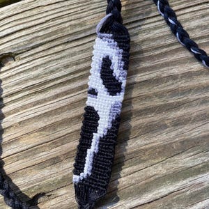 Op de afbeelding: Zwart-witte vriendschapsband met een gevlochten koord. De armband is gemaakt met een zwart-wit patroon.