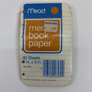 Könnte beinhalten: Eine Packung Mead Notizbuchpapier mit 80 Blatt in der Größe 12,7 cm x 7,6 cm. Das weiße Papier hat blaue horizontale Linien und eine blau-orange Kopfzeile mit dem Text 'mead' und 'memo book paper'. Ein Revco-Preisschild zeigt .39 an.