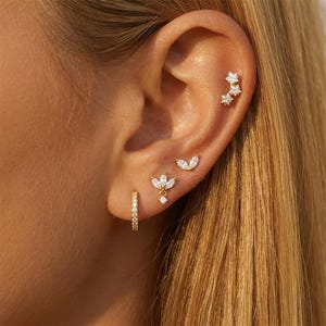 Puede incluir: Un juego de tres tazas de cerámica con un acabado moteado y mate. Las tazas son de color crema, gris claro y gris oscuro. Cada taza tiene un diseño simple y moderno y un asa redondeada. Las tazas están apiladas.