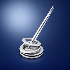 Könnte beinhalten: Ein silberfarbener Metallstift, der in einem kreisförmigen, spiralförmigen Sockel schräg steht. Der Stift hat einen glatten, konisch zulaufenden Körper, während der Sockel aus mehreren gestapelten, konzentrischen Ringen besteht, die Halt bieten.