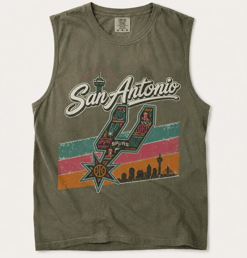 Puede incluir: Una camiseta sin mangas de color verde oliva con el texto San Antonio en letra blanca. Un logotipo de los Spurs relleno de patrones coloridos se sit&uacute;a sobre franjas horizontales en verde azulado, rosa y naranja, con una silueta urbana.