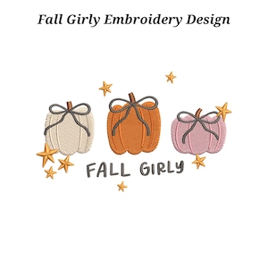 Pode incluir: Um design de bordado apresentando três abóboras nas cores creme, laranja e rosa, cada uma amarrada com um laço cinza escuro. O design inclui várias estrelas douradas e o texto FALL GIRLY em letras cinza escuro. Composição centralizada.