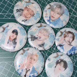 May include: Seven round pinback buttons featuring images of young people. Each button has a different image, with a light blue and white background. Some buttons have text in a foreign language.