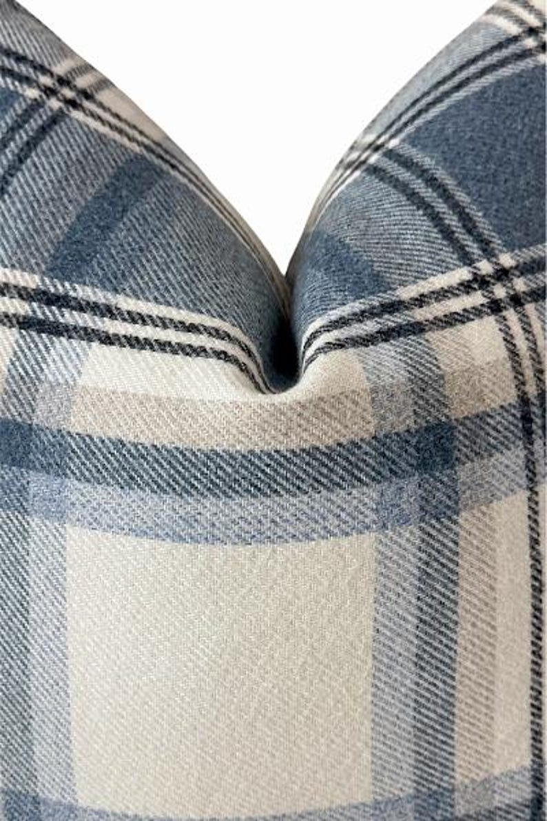 Pu&ograve; includere: Primo piano di un cuscino a quadri blu, bianco e beige. Il cuscino ha un aspetto morbido e strutturato con un classico motivo a quadri. La combinazione di colori &egrave; un mix di blu chiaro e scuro, bianco e beige, creando un'estetica accogliente e invitante.
